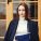 Beautiful girl in a black coat. Cute lady near building. Woman at the door
