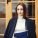 Beautiful girl in a black coat. Cute lady near building. Woman at the door