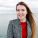 Portrait of smiling pretty girl with flying long hair enjoys good weather and walking by the sea with true happy emotions